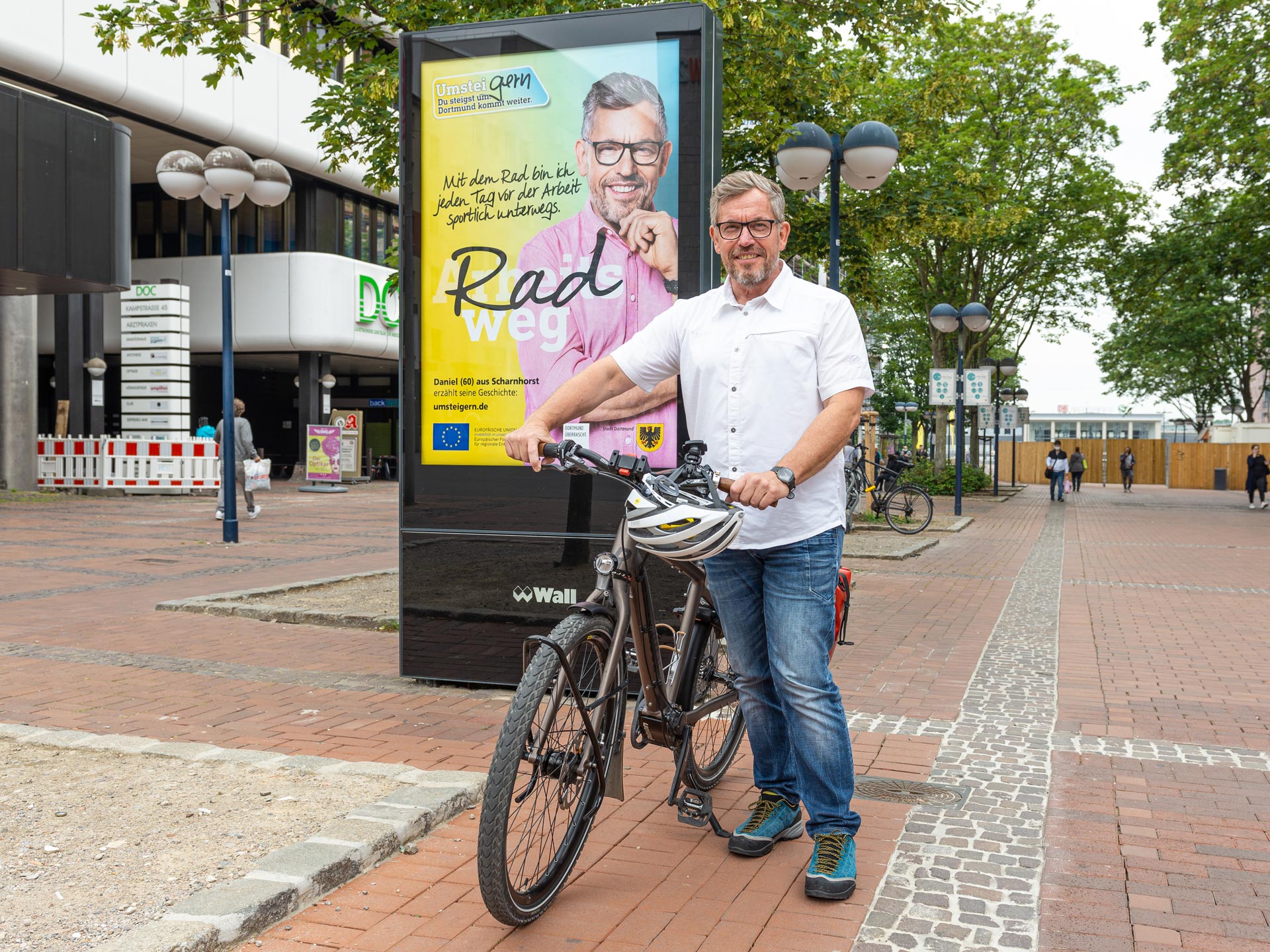 Fahrrad-Botschafter Daniel steht vor UmsteiGERN-Plakat der Emissionsfreien Innenstadt Dortmund