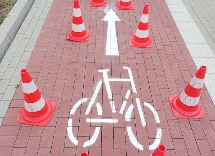 Zu sehen ist ein roter Fahrradweg welcher durch ein Symbol die Richtung der Fahrradfahrer angibt. 